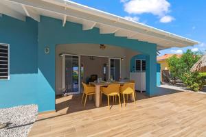 a blue house with a table and chairs on a deck at Villa Monte Azul in Willemstad