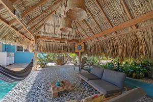 a living room with a couch and hammock under a straw roof at Villa Monte Azul in Willemstad