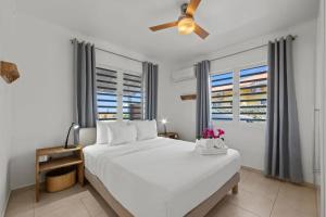 a bedroom with a white bed with a ceiling fan at Villa Monte Azul in Willemstad
