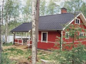 a red house with a porch in the woods at Holiday Home 6332 by Interhome in Rantakylä