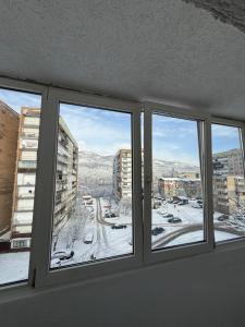a room with three windows with a view of a city at ADA Residence Lupeni acces rapid catre Straja Ski Resort in Lupeni