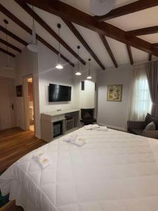 a large white bed in a room with a tv at Hani i Gjelit Hotel, Korce in Korçë