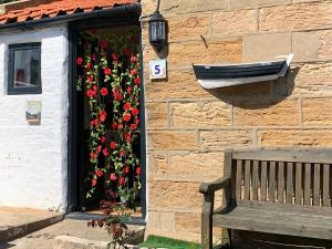 a wooden bench sitting in front of a building with flowers at Fisherman's Cottage, Staithes in Staithes