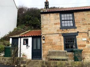 a brick house with a bench in front of it at Fisherman's Cottage, Staithes in Staithes