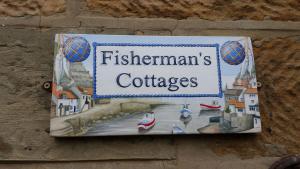 a sign on the side of a wall with a sign forflemwegianos at Fisherman's Cottage, Staithes in Staithes