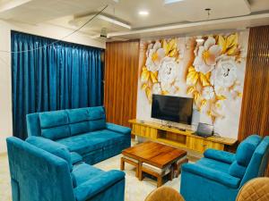 a living room with blue couches and a television at Devs Villa Amansara above the sky in Pune