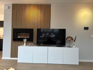 a living room with a tv and a white cabinet at Luxe woning met verwarmd zwembad in Genk