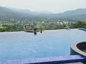 a man in a swimming pool with a view at Devs Villa Amansara above the sky in Pune