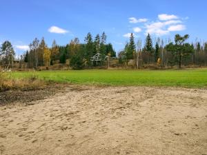 a dirt road in front of a field with a house at Holiday Home Koskiharju by Interhome in Säynetlahti