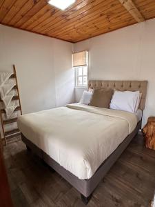 a large bed in a room with a wooden ceiling at La Casona Papudo in Papudo