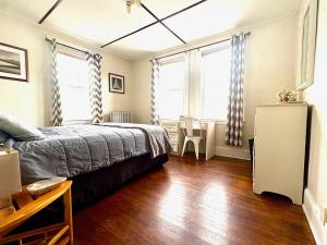 a bedroom with a bed and wooden floors and windows at The Wadsworth Suite A2 in Hartford