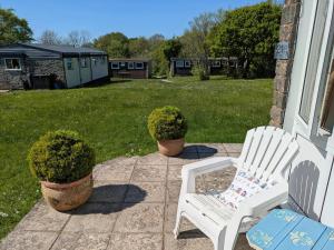 two white chairs sitting on a porch with plants at 21 The Glade in Bude