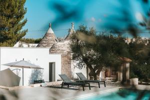 a house with a swimming pool and two chairs and an umbrella at Trullo Alisia - TrulloExperience in Putignano