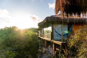 a house with a thatched roof in the jungle at Alizées Moreré in Ilha de Boipeba