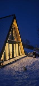 a cabin with a lit up window in the snow at Wild Hill Apuseni in Gârda de Sus
