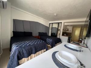 a small bedroom with two beds and a sink at SKY INN Oficial Acapulco Suites & Condo Mediterrane in Acapulco +39 photos