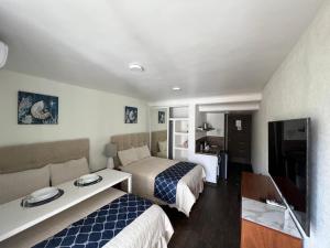 a hotel room with two beds and a tv at SKY INN Oficial Acapulco Suites & Condo Mediterrane in Acapulco