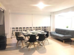 a dining room with a table and chairs and a couch at SKY INN Oficial Acapulco Suites & Condo Mediterrane in Acapulco