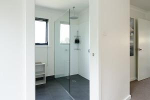 a white bathroom with a glass shower stall at Modern Newnham Retreat in Newnham +32 photos