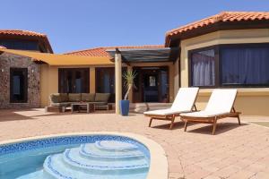 a swimming pool with two chairs and a house at Casa Tranquilidad in Willemstad