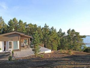 a small house with a deck in front of trees at Holiday Home Västantill by Interhome in Hitis