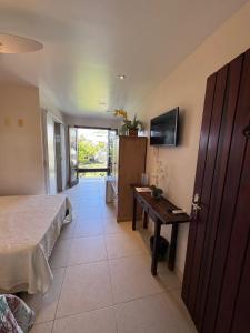 a bedroom with a bed and a table and a television at Oceanica 1000 Beachfront Suites in Saquarema