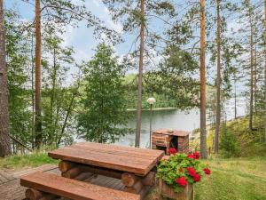 a picnic table with flowers and a bird house next to a lake at Holiday Home Salmela by Interhome in Ollila