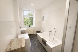 a white bathroom with a tub and a sink at Ferienwohnung Zentralglück in Meerane