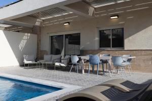 a patio with a table and chairs next to a swimming pool at וילה פאן 4 חדרי שינה בריכה מחוממת Villa Fun 4 BR Heated Pool in Eilat
