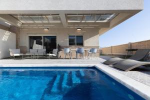 a swimming pool with chairs and a table on a patio at וילה פאן 4 חדרי שינה בריכה מחוממת Villa Fun 4 BR Heated Pool in Eilat