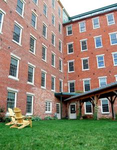 a large brick building with two chairs in front of it at The Common Man Inn & Restaurant in Claremont