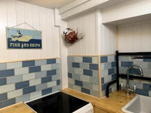 a kitchen with blue and white tiles on the wall at Old Jack's Cottage, Staithes in Staithes +56 photos