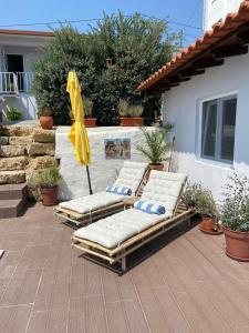 three lounge chairs with an umbrella on a patio at Coastal Vineyard Hideaway in Torres Vedras