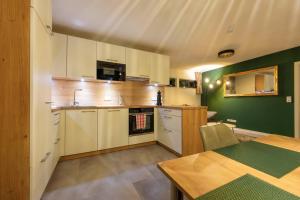 a kitchen with white cabinets and a green wall at Das Chalet in Himmelkron