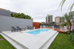 a swimming pool with two chairs next to a building at Azurine Pousada in Passo de Torres