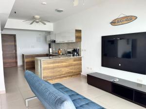 a living room with a blue couch and a tv at Departamento frente al mar - Resort Playa Azul in Tonsupa