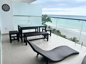 a balcony with a table and chairs and the beach at Departamento frente al mar - Resort Playa Azul in Tonsupa