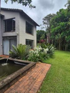 a house with a pond in front of a yard at The Macadamia Nut Farm House in White River