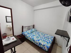 a small bedroom with a bed and a table at Guayacan Hostel in Cali