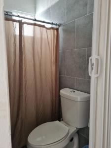 a bathroom with a toilet and a shower curtain at La casa del mar in Manzanillo
