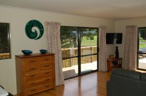a living room with a couch and a sliding glass door at Kohinui Glade Holiday Cottage in Parua Bay