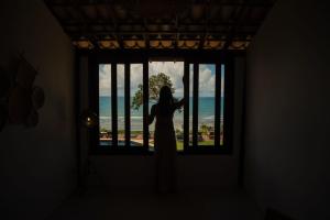 a woman standing in a window looking out at the ocean at Beijo do Vento Pousada in Arraial d'Ajuda +102 photos