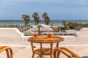 a small table with two glasses on it on a patio at Uliveus - Villa Duna fronte mare in Faccia di Trippa