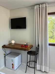 a room with a table and a chair and a television at Pousada Sítio Rústicu's in Domingos Martins
