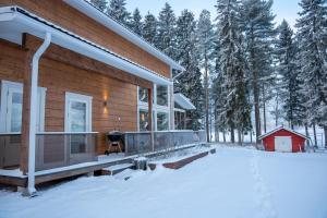 a house with a deck in the snow at Villa Siltasaari in Sotkamo