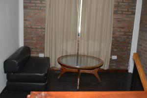 a living room with a glass table and a leather couch at Casa Tapyí Paso in Paso de la Patria