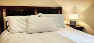 a white bed with white pillows and a lamp at Serenity Cottages in Richmond