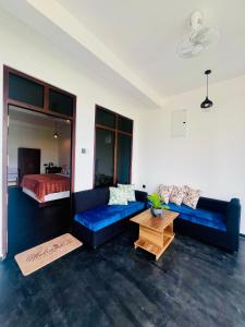 a living room with two blue couches and a bed at ANB Surf View in Tangalle