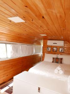 a bedroom with a white bed in a wooden ceiling at Refúgio Veadeiros Ônibus in Sao Jorge