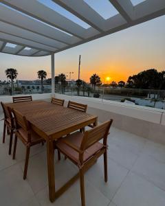a wooden table and chairs on a balcony with the sunset at Penthouse duplex with jacuzzi, 5 min to beach in Chipiona